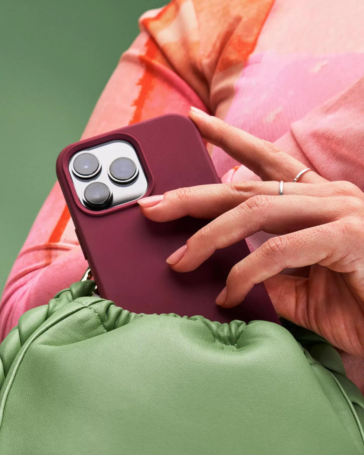 Body holding a phone with a dark red phone case