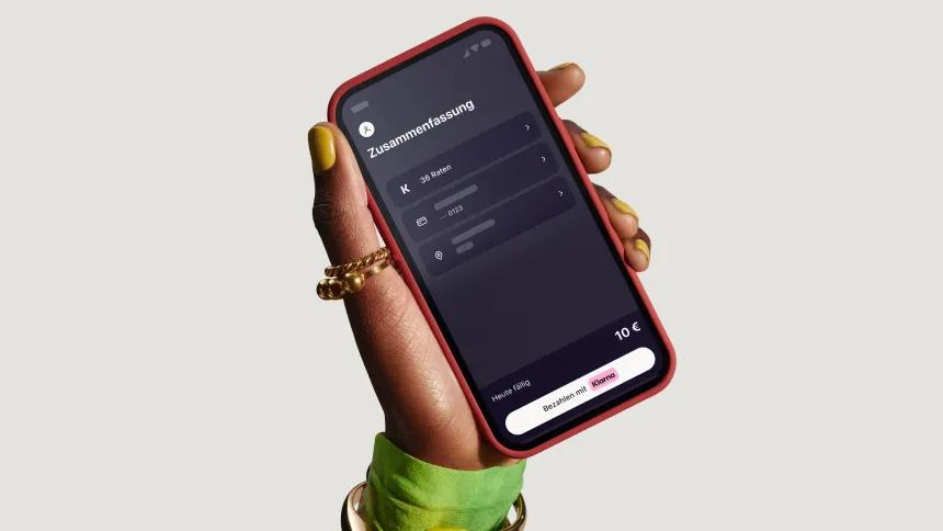 Hand holding phone with Klarna app open