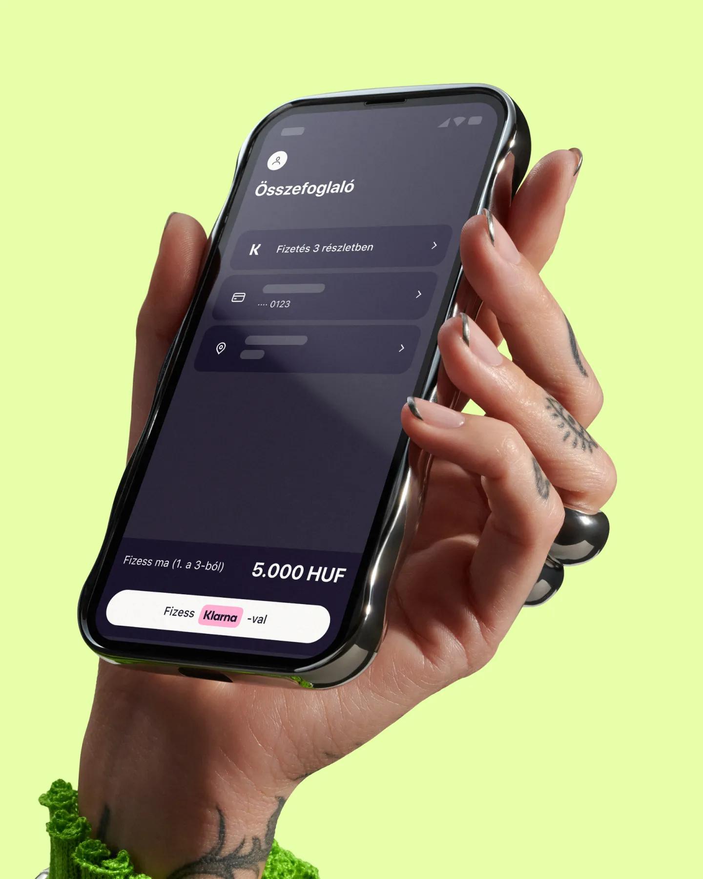 Hand holding phone with Klarna app open on a yellow background