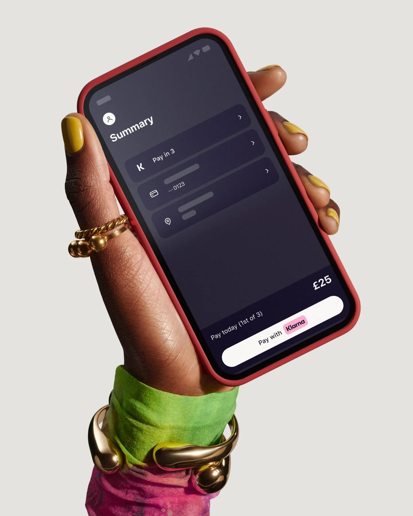 Hand holding a phone with a screen of the Klarna app