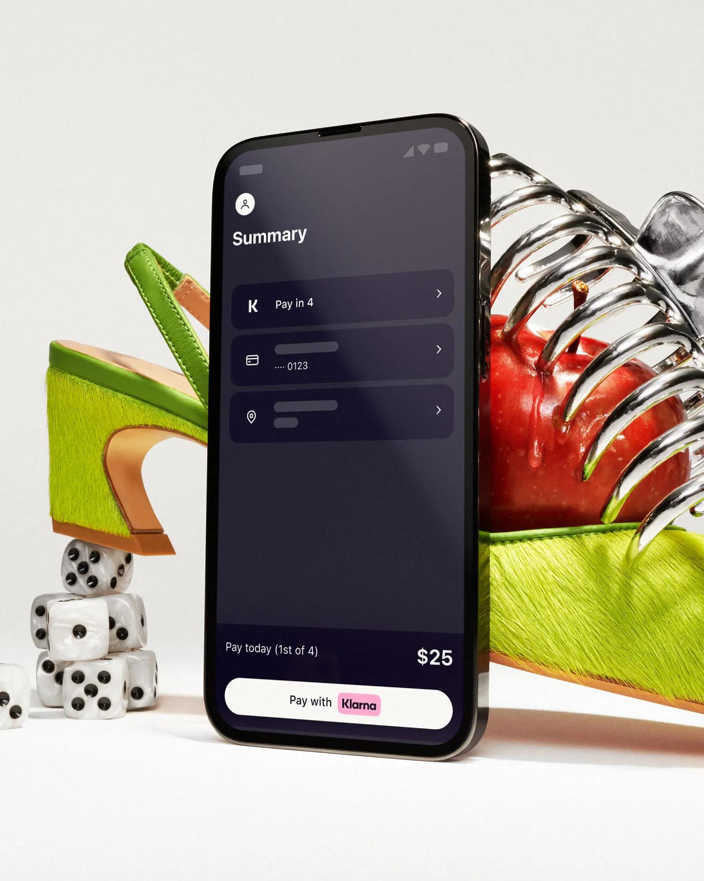 Standing phone with Klarna app openin front of an artistically styled shoe