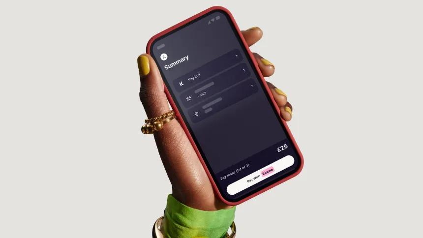 Hand holding a phone with a screen of the Klarna app