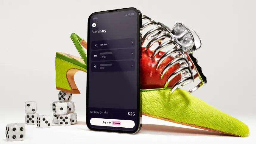 Standing phone with Klarna app open in front of an artistically styled shoe