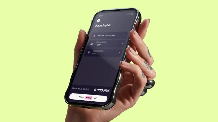 Hand holding phone with Klarna app open on a yellow background